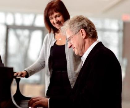 woman teaching an adult male student at the piano